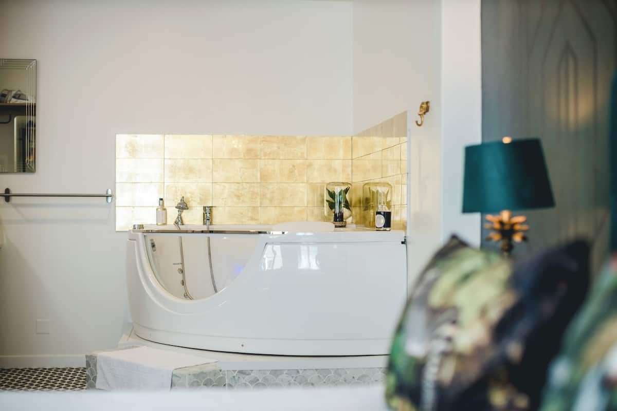 A modern bathroom with a freestanding bathtub, a towel rack, and a mirror.