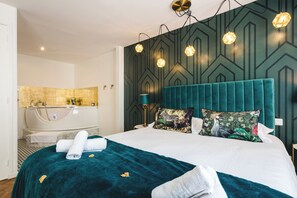 Quarto de hotel moderno com uma cama grande, banheiro separado e parede com padrão geométrico.