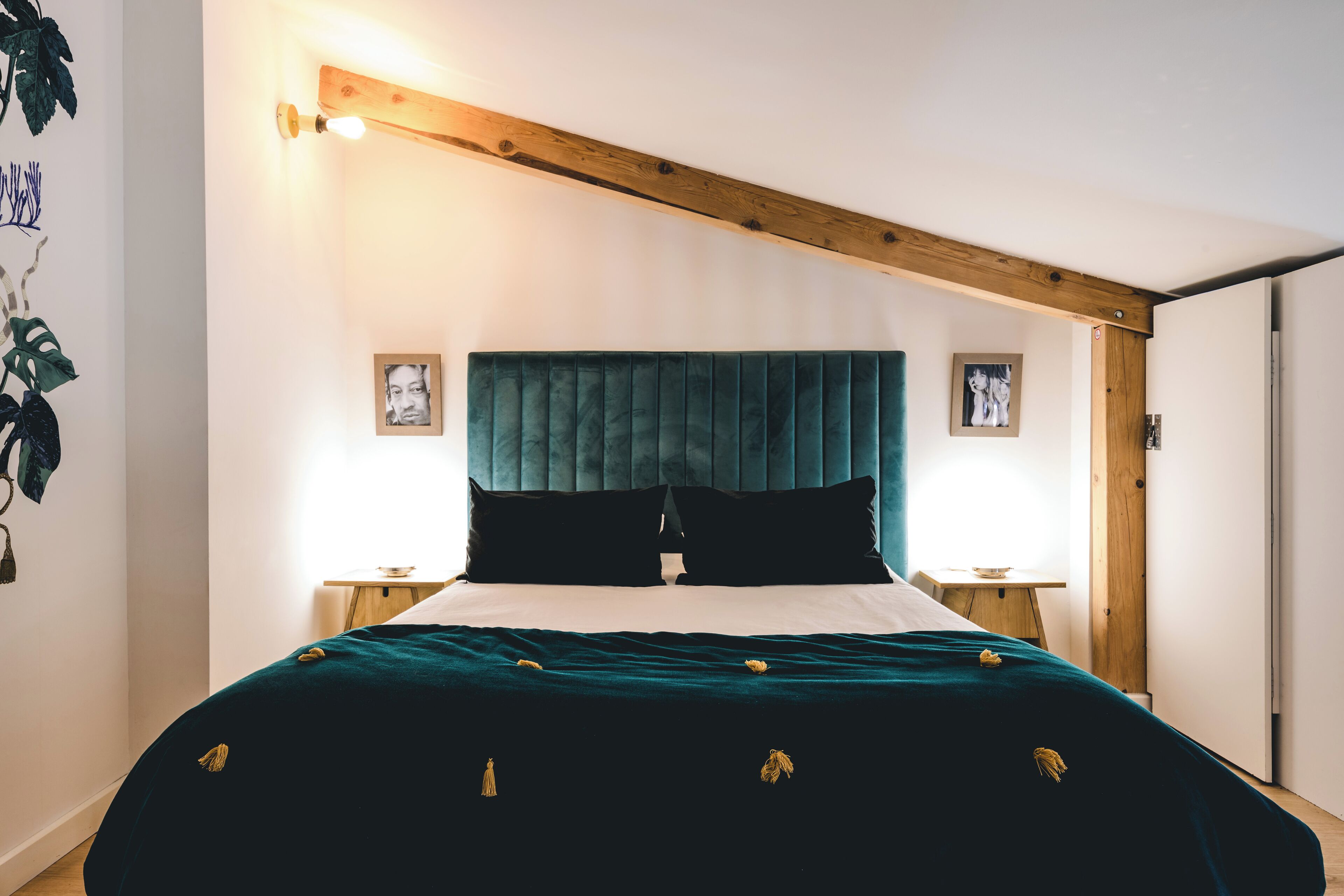 A bedroom with a large bed, wooden beams, and two bedside tables with lamps.