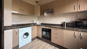 Une cuisine moderne avec des meubles de couleur beige, un lave-linge encastré, un four à micro-ondes et une cuisinière.