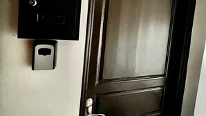 Une porte dotée d’un clavier pour l’ouverture et d’un système d’interphone fixé au mur.