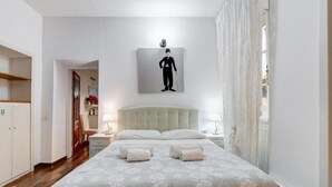 Habitación de hotel con una cama grande, cabecero, mesita de noche con lámpara y un cuadro en la pared.