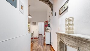 Un pasillo con piso de madera, paredes blancas y una chimenea con un adorno en la parte superior.