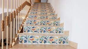 A staircase with ornate, colorful tiles and a wooden handrail. - Sea Whisper Home -Sunset, Sea, Easy Stay, Shops (Praiano)