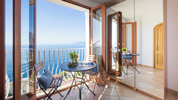 A balcony with a table, chairs, and a view of the sea. - Sea Whisper Home -Sunset, Sea, Easy Stay, Shops (Praiano)