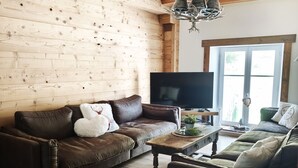 A cozy living room with a wooden ceiling, a brown leather sofa, a wooden coffee table, and a television. - Mountain Chalet Hiking, Nature, Skiing near Gérardmer (Le Valtin)