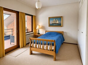 A bedroom with a wooden bed, a painting of a sailboat, a window with curtains, and a radiator. - Sæbygaard guesthouse (Hong)