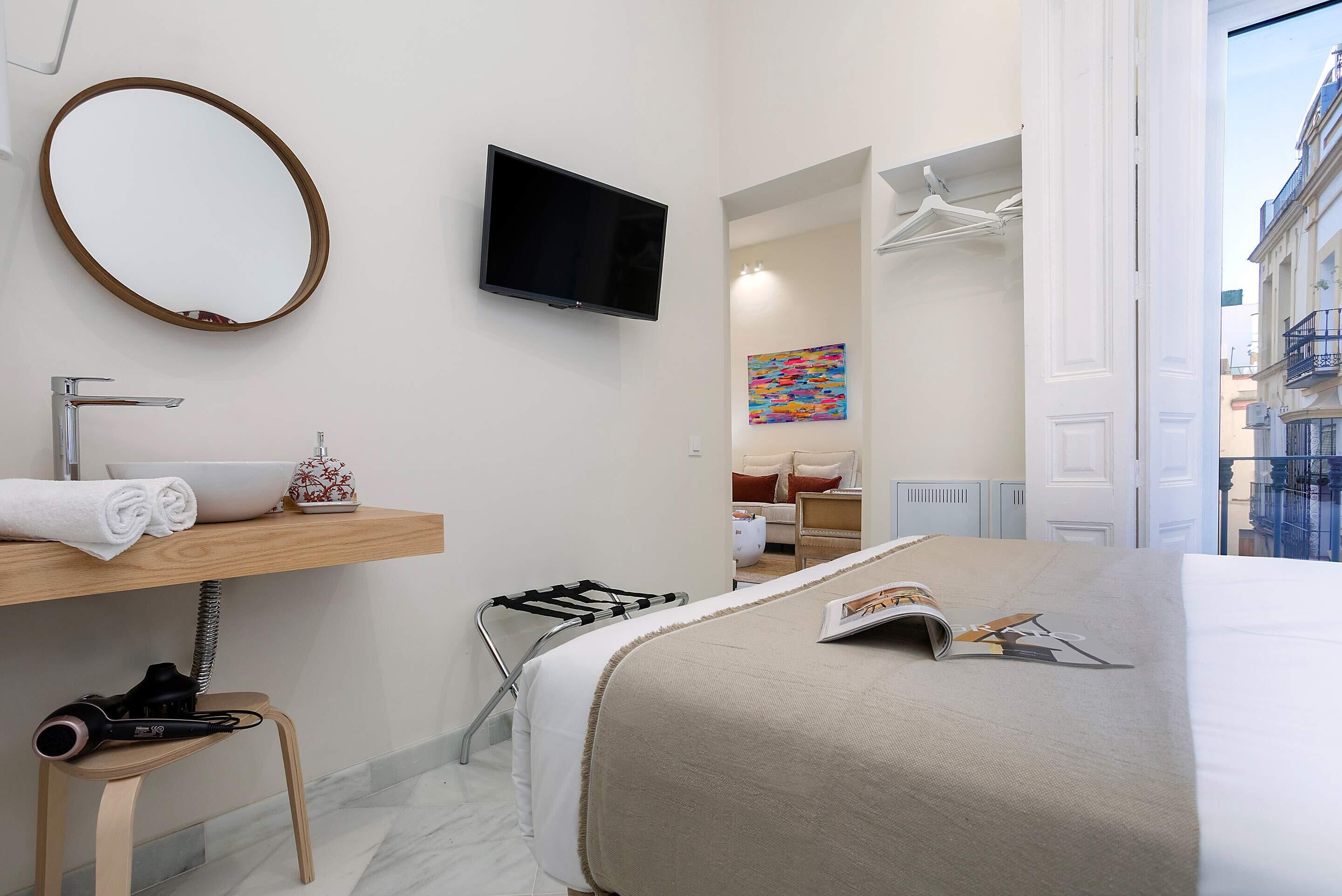 Ein Hotelzimmer mit Bett, Fernseher, Bad mit Waschbecken und Handtuchhalter sowie Blick auf die Stadt.