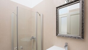 A bathroom with a glass-enclosed shower, a white sink, and a mirror with an ornate frame. - Villa Sokol - Belle Epoque studio (Opatija)