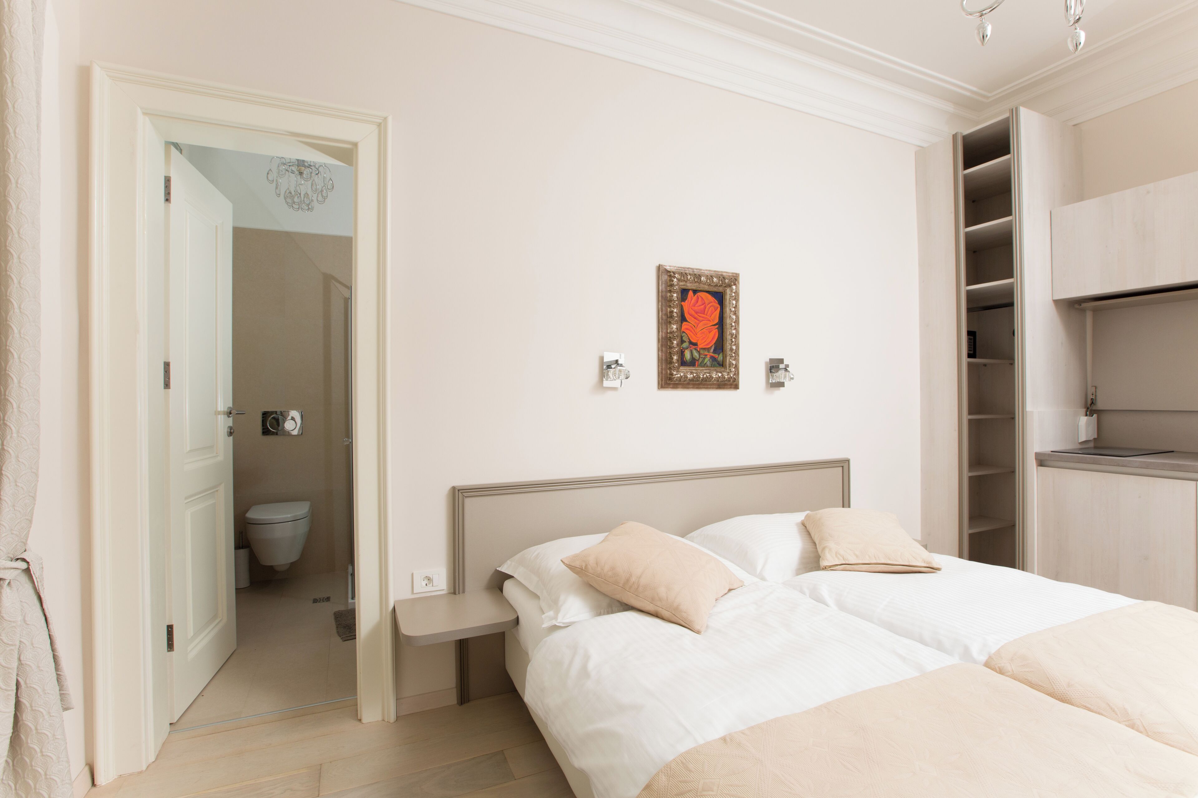 A bedroom with a bed, bedside tables, a wardrobe, and a bathroom visible through an open door.