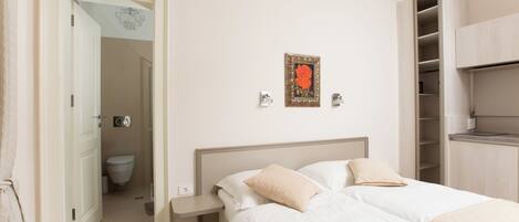 A bedroom with a bed, bedside tables, a wardrobe, and a bathroom visible through an open door.