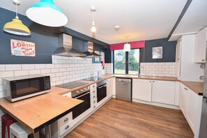 A kitchen with white cabinets, a microwave, a stove, a dishwasher, and a wooden countertop. - Spacious 7 Bedroom Budget Apartment in Headingley (Headingley)