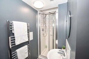 A modern bathroom with a glass-enclosed shower, a white sink, and a towel rack with multiple towels. - Budget 5BR Apartment in the Heart of Headingley (Headingley)