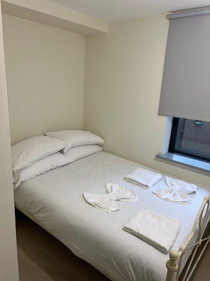 A single bed with white linens, pillows, and towels arranged on the bed. - Convenient 4BED Budget Apartment in Headingley (Headingley)