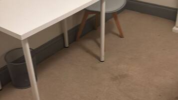 A white table with metal legs, a grey chair, and a carpeted floor.