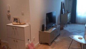 En stue med tv, et lille bord og et skab.