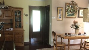 A dining area with a wooden table and chairs, a chandelier, and a cabinet with glass doors.