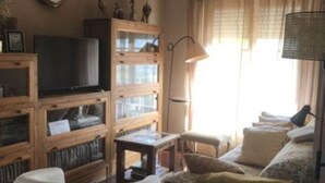 A living room with a television, wooden shelving, a lamp, and a sofa.