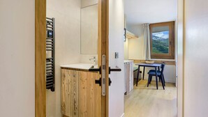 Ein modernes Badezimmer mit einem Holzkosmetikschrank, einem Handtuchhalter und einer Dusche.