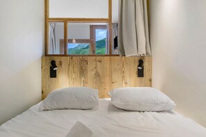 Una cama con ropa de cama blanca, un cabecero de madera y una ventana con cortinas.