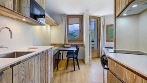 Eine kompakte Küche mit integriertem Mikrowellenherd, Spüle und Fenster mit Blick ins Freie.