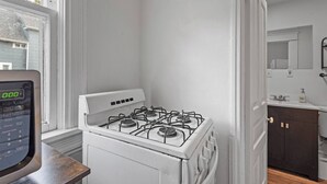 Een keuken met een witte kookplaat, een digitale klok en uitzicht op buiten.