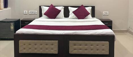 A bedroom with a bed, a nightstand, a dresser, a ceiling fan, and a large framed picture on the wall.