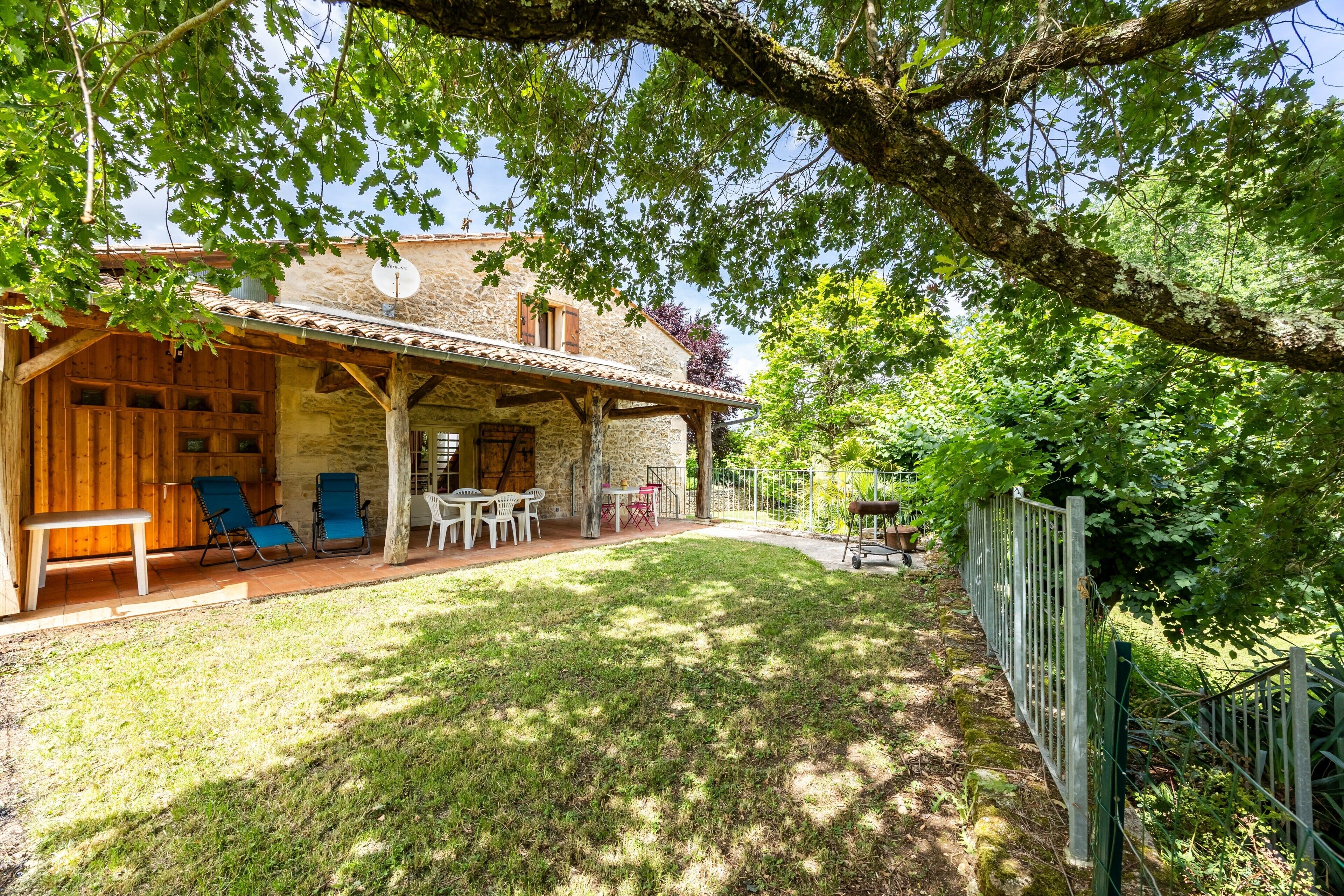 Un bâtiment en pierre doté d’un patio couvert, d ’un espace extérieur aménagé pour s’asseoir et d’un jardin clos.