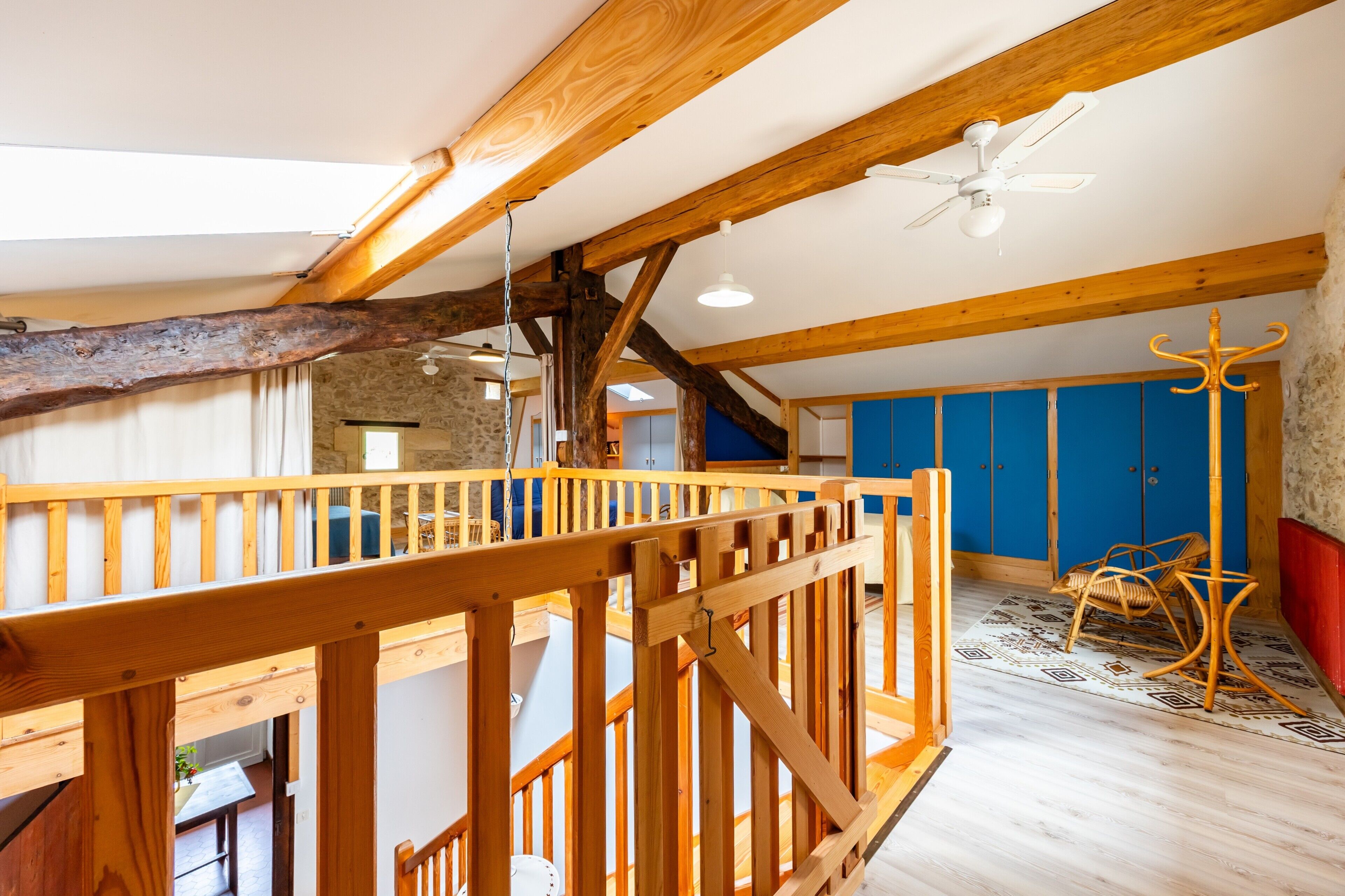 A loft-style room with exposed wooden beams, a ceiling fan, and a view of the interior.