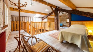 Ein rustikaler Raum mit einem Bett, Holzbalken, einer Bank und einer Treppe.