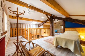 A rustic room with a bed, wooden beams, a bench, and a staircase. - Gîte la Sarpette – Secluded Retreat in Nature (Sainte-Radegonde)
