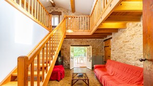 Ein rustikales Interieur mit einer Holztreppe, einem roten Sofa und einer Steinwand.