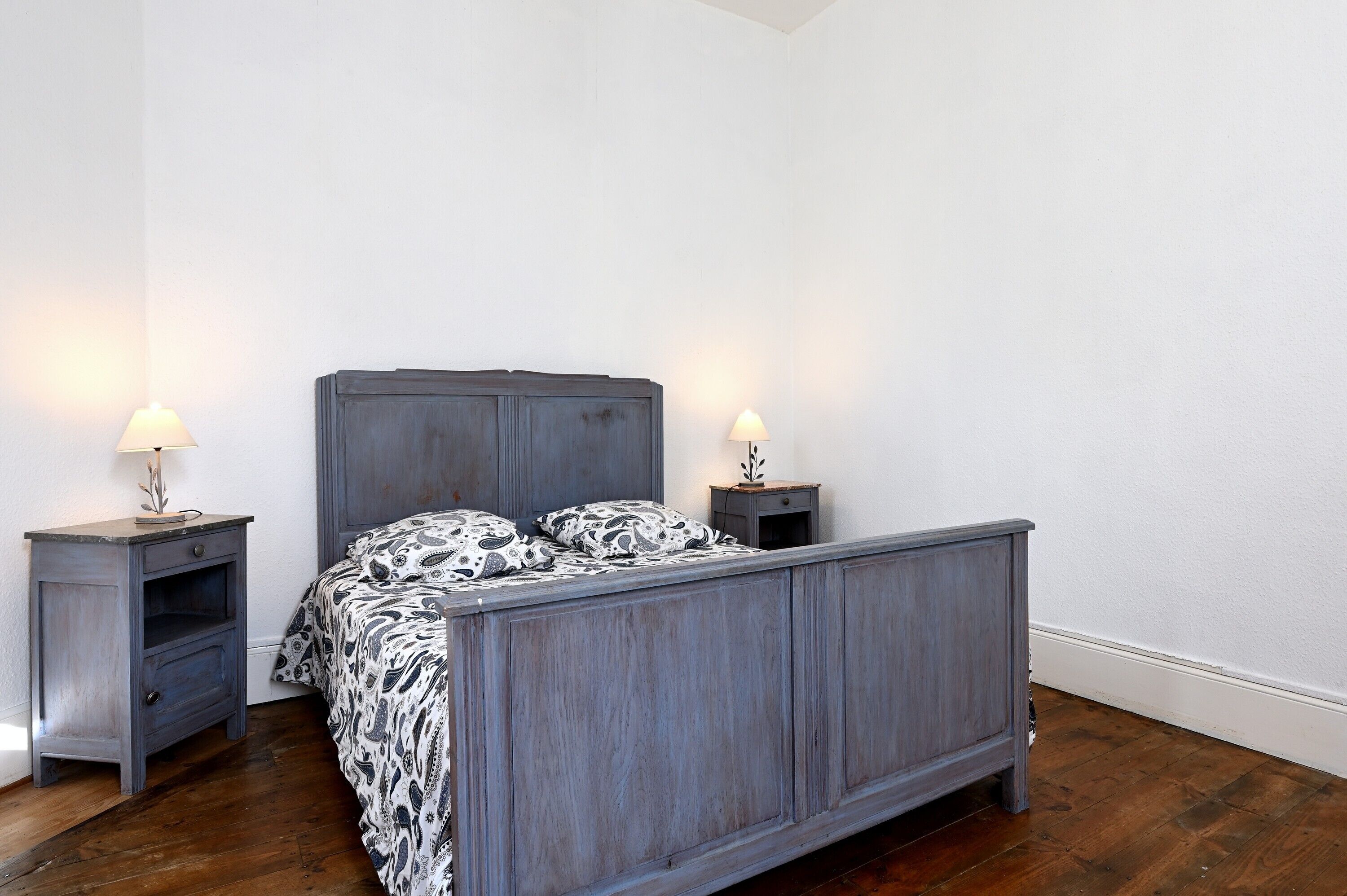 Un dormitorio con una cama de madera, dos mesitas de noche y un tocador.