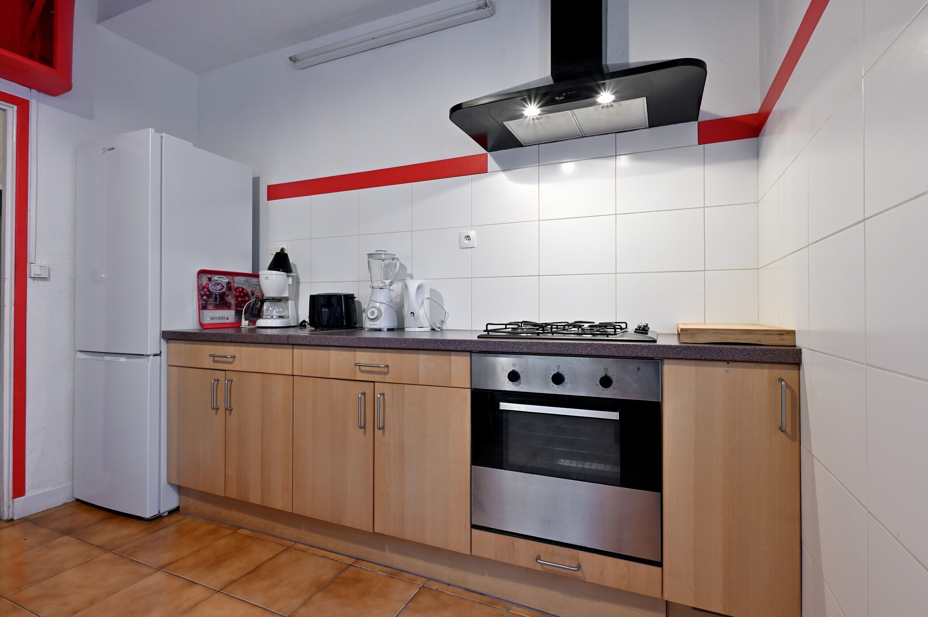 Eine Küche mit Kühlschrank, Herd, Backofen und verschiedenen Geräten.