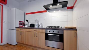 Eine Küche mit Kühlschrank, Herd, Backofen und verschiedenen Geräten.