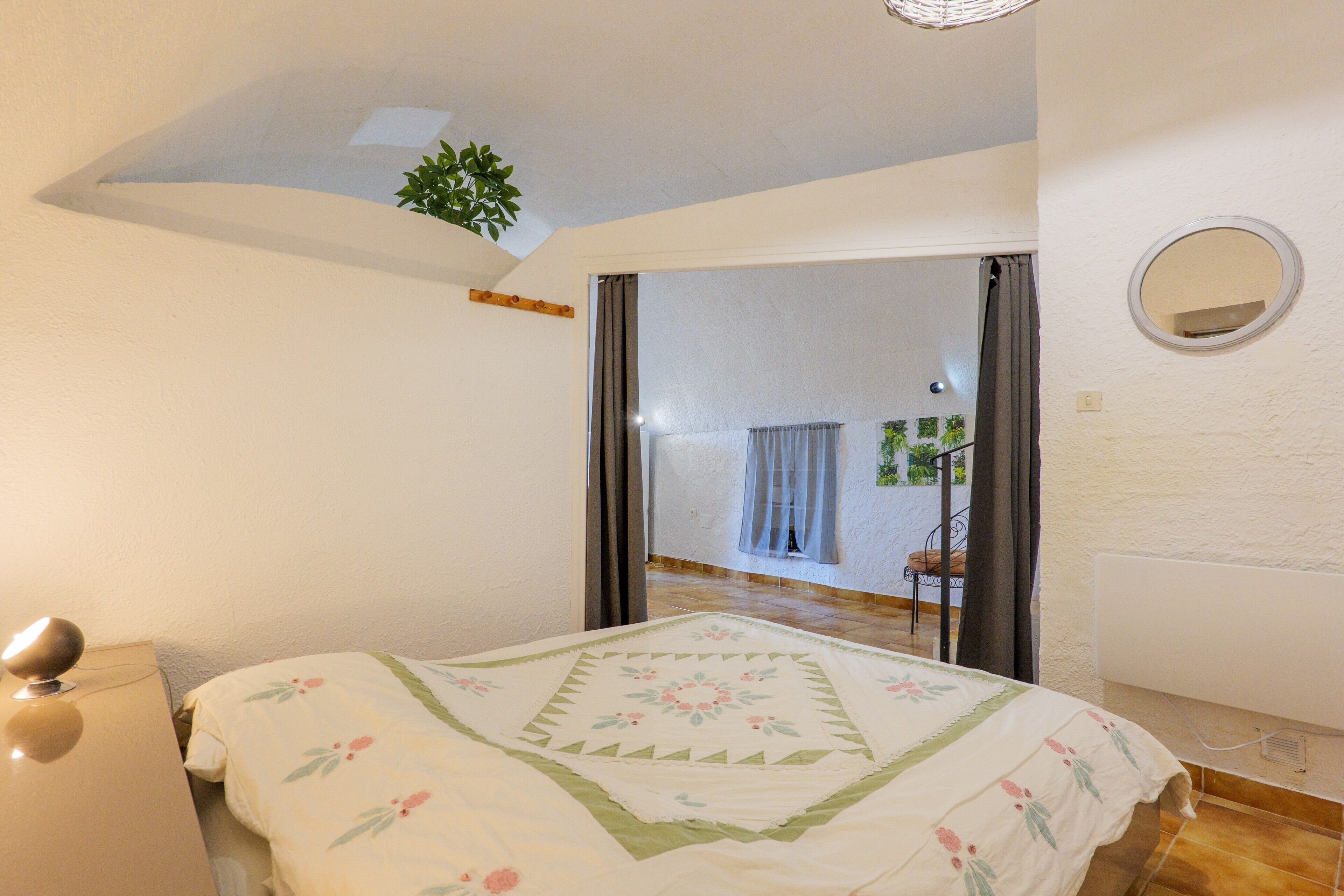 Una camera da letto con un letto, un comodino, uno specchio e vista su un balcone.
