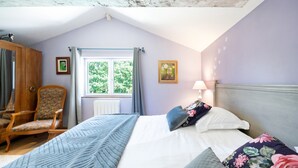 Een slaapkamer met een bed, een stoel, een raam en een lamp.