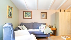 Una sala de estar con un sofá gris, un aparador de madera y cuadros en las paredes.