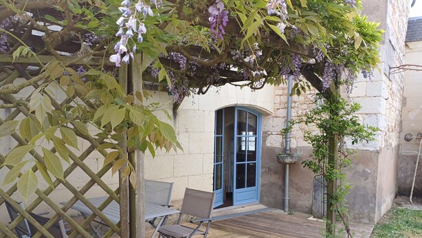 Una terraza de madera con una puerta azul, celosía y una planta en maceta.