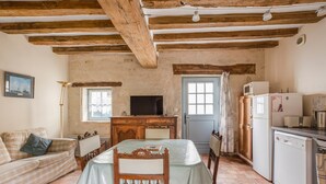 Una cocina rústica con una mesa de madera, un sofá, un televisor y un refrigerador.