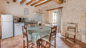 Una cocina rústica con vigas de madera a la vista, un rebozado de azulejos y una zona de comedor con una mesa y sillas.