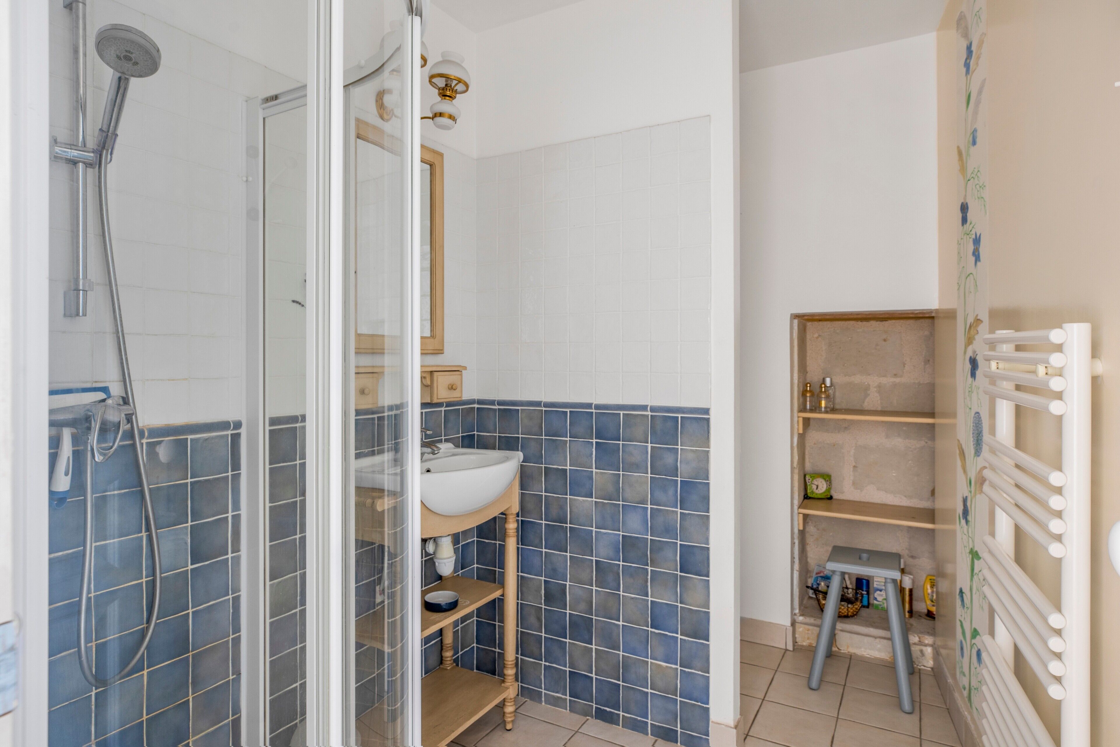 Une salle de bain avec une douche à parois de verre, un lavabo, un miroir et un mur carrelé.