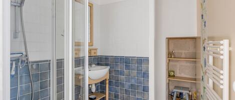 Une salle de bain avec une douche à parois de verre, un lavabo, un miroir et un mur carrelé.