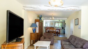 A living room with a television, a sofa, a coffee table, a lamp, and a cabinet. - Gite de la Barthe – near Dax (Garrey)
