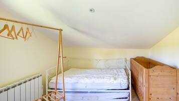 Una camera da letto con un letto, una culla in legno, un termosifone e un appendiabiti in legno.