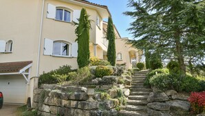 A two-story building with a stone staircase leading to a balcony, surrounded by greenery and a clear sky. - Bed and Breakfast 'Maison D'hotes Dolce Vita' with Mountain View, Shared Pool and Wi-Fi (Veyssilieu)