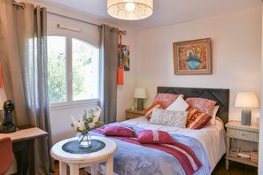 A bedroom with a bed, a bedside table, a lamp, a window with curtains, and a painting on the wall. - Bed and Breakfast 'Maison D'hotes Dolce Vita' with Mountain View, Shared Pool and Wi-Fi (Veyssilieu)