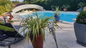 A pool area with lounge chairs, potted plants, and a decorative archway. - Bed and Breakfast 'Maison D'hotes Dolce Vita' with Mountain View, Shared Pool and Wi-Fi (Veyssilieu)