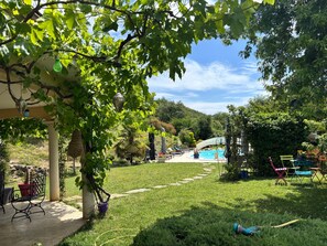 Un jardín con piscina, mobiliario exterior y una pérgola.
