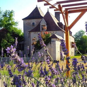 Un bâtiment en pierre doté d’une tour, entouré de champs de lavande.